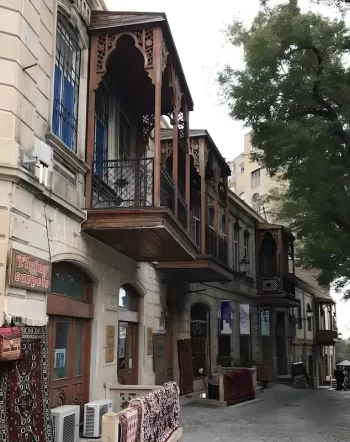 زقاق تراثي في المدينة القديمة إيتشيريشهير في أفضل الأماكن السياحية في باكو 2026، أذربيجان، يظهر فيه مبانٍ حجرية تقليدية ومحلات السجاد