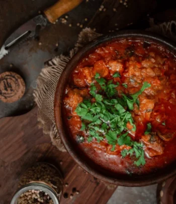 طبق تشاخوخبيلي جورجي من الدجاج المطهو بصلصة الطماطم والأعشاب في وعاء فخاري