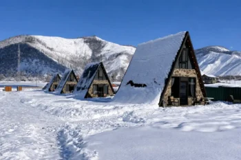 أكواخ خشبية في جبال جورجيا خلال فصل الشتاء مغطاة بالثلوج – أجواء سياحية شتوية في جورجيا