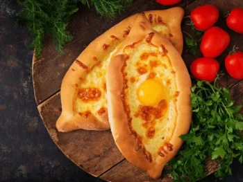 خاتشابوري أدجاري الجورجي بخبز مفتوح محشو بالجبن مع بيضة في المنتصف على طاولة خشبية في المطبخ الجورجي