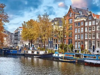 قناة مائية في أمستردام خلال فصل الخريف مع مبانٍ تاريخية وأشجار بألوان ذهبية