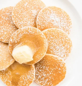 فطائر بوفرتشيس هولندية صغيرة مرشوشة بالسكر البودرة مع قطعة زبدة في المنتصف