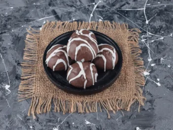 حلوى بوسشه بول الهولندية مغطاة بالشوكولاتة ومحشوة بالكريمة مقدمة على طبق أسود