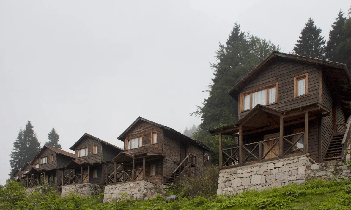 حجز الأكواخ في طربزون 2026 صورة لأكواخ خشبية في طرابزون وسط الضباب والطبيعة الجبلية بإطلالة هادئة